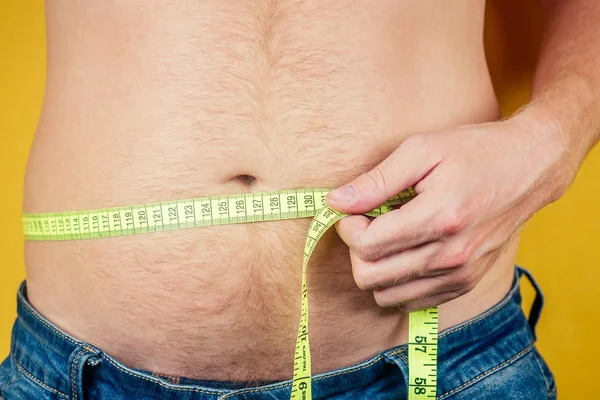 Um homem gordo e uma fita métrica na barriga. conceito de nutrição não saudável — Fotografia de Stock