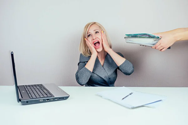 attractive smart blonde multitasking woman business lady in stylish business suit working with laptop and a bunch of folders screams in panic in office . business concept and deadline