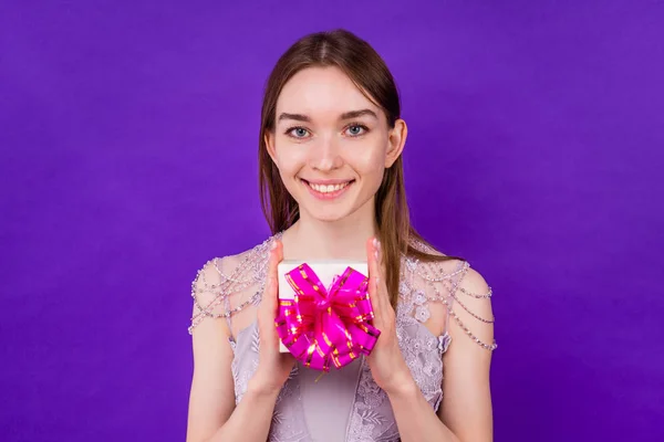 Lächeln überrascht schöne Braut mit Make-up hält Geschenkbox im Studio auf violettem Hintergrund. Konzept der Geburtstags- und Hochzeitsfeier — Stockfoto