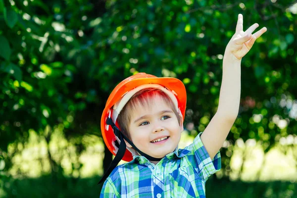 Pequeño niño constructor en la construcción casco hardhat sobre fondo verde parque —  Fotos de Stock