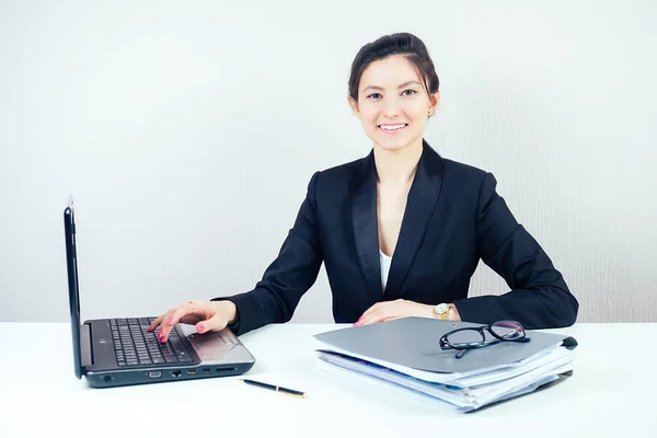 Attractive brunette businesswoman in a stylish business suit working in the office with a laptop. concept of business and economics Stock Image