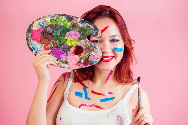 Schmutzige Visagisten-Make-up-Artist Flecken von Farbe auf der Gesichtspalette in den Händen auf rosa Hintergrund im Atelier — Stockfoto