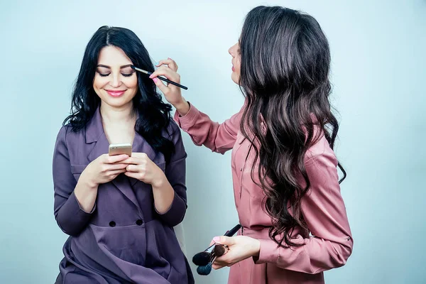 Bela mulher make-up artista visagiste aplicando cosméticos make-up no rosto do cliente feminino no estúdio salão de beleza  . — Fotografia de Stock