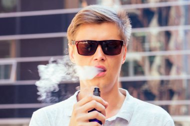 Beyaz gömlekli genç adam modern bir arka planda sigara içiyor.