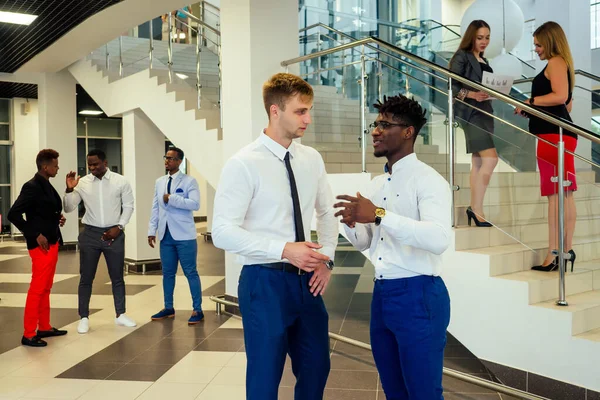 Porträtt av ambitiösa affärsteam olika etnicitet multinationella människor i snygg kostym få kommunicera tillsammans i lobbyn i moderna kontoret . — Stockfoto