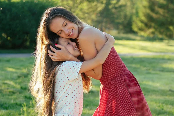 Aantrekkelijke moeder in een cocktail jurk knuffelen haar lieve mooie dochter lang haar in het park zomer reis. gezond vrouwenconcept — Stockfoto