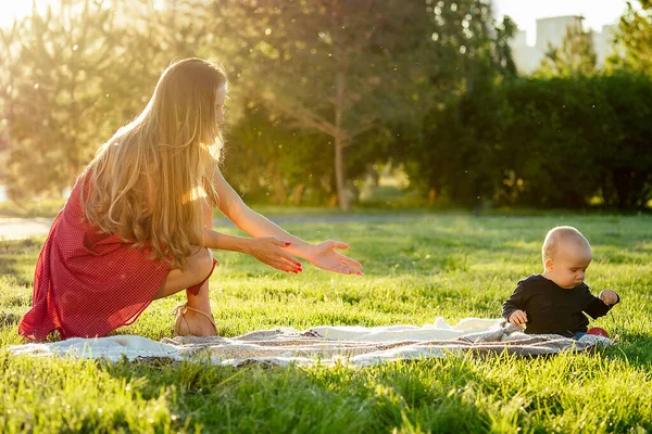 Klein jongetje samen met moeder op een deken in het park in de zomer — Stockfoto