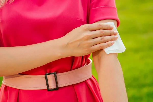 Parte del cuerpo de una joven en un parque rosa. chica usando mojado toallitas el sudor en el brazo — Foto de Stock
