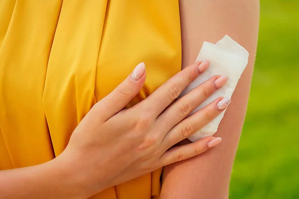 公園の黄色いドレスを着た若い女性の体の一部ですぬれたワイプで腕に汗を拭く少女 — ストック写真