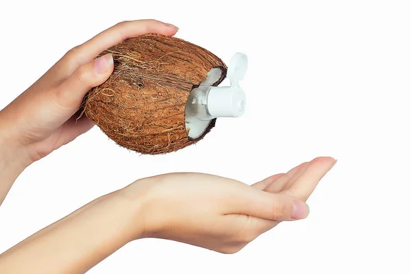Бутылка с кокосовым маслом и колпачок в руке на белой изоляции — стоковое фото