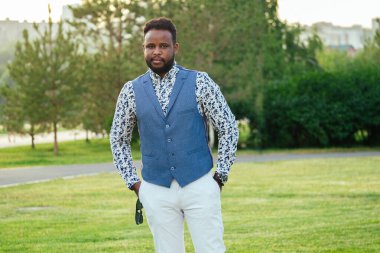 Bir yaz parkında şık takım elbiseli genç ve yakışıklı bir Afro-Amerikan. İş çıkışı ofiste yürüyen siyahi bir işadamı.