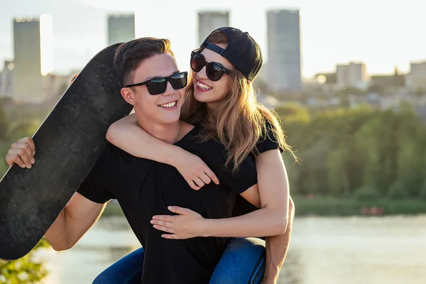 active couple in love sport skating in the summer park. beautiful woman and man have fun with skateboard longboard background the river urban city . active lifestyle among young people