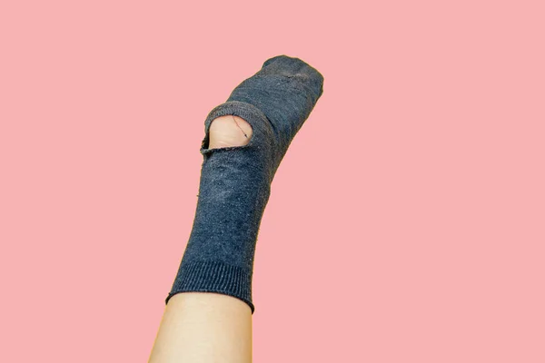 Old smelly sock full of holes on the leg on a pink background — Stock Photo, Image