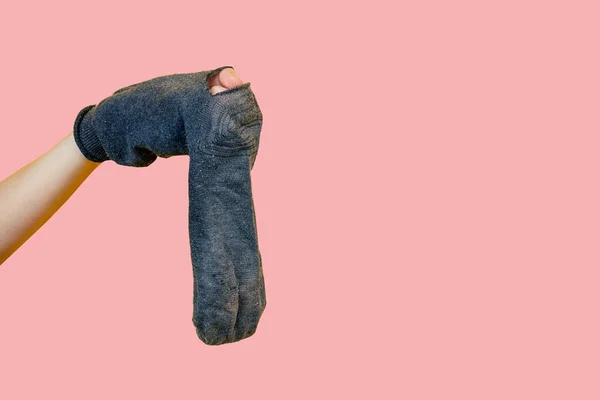 Старий смердючий дірявий шкарпетка в руці на рожевому фоні — стокове фото