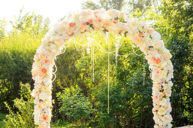 Kırsal düğün töreninde beyaz pembe kumaşlı ve ahşap elementli çiçek kemeri. Düğün kemeri süslenmiş.