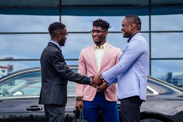 Um grupo de três amigos de negócios afro-americanos elegantes empresários de moda ternos de negócios reunião handshaking em um verão ao ar livre. conceito de bom negócio bem sucedido — Fotografia de Stock