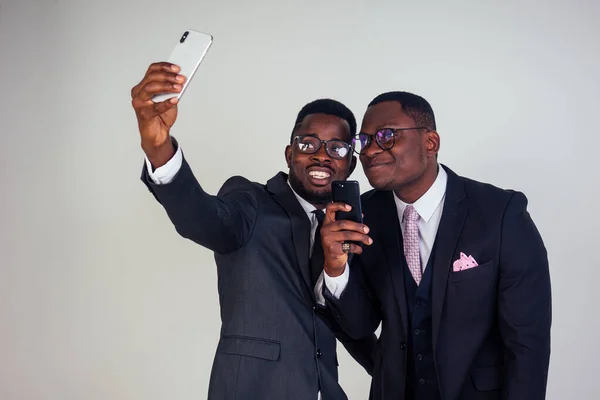 two business partner African American man taking selfie on a smartphone white background in studio. closeup portrait