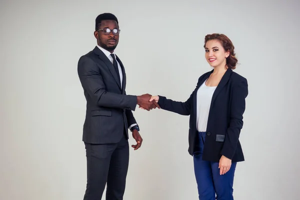beautiful and young indian woman journalist interviews handshake wiht African american bank manager owner ceo business man in the studio on a white background. multinational teamwork high five