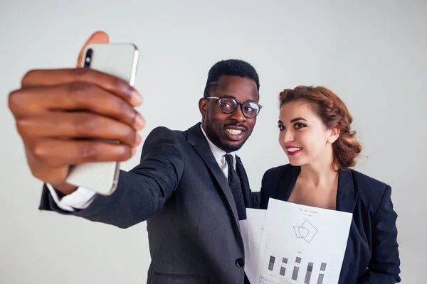 beautiful indian female business leader with multiracial business partner African American man taking selfie on a smartphone white background in studio. closeup portrait