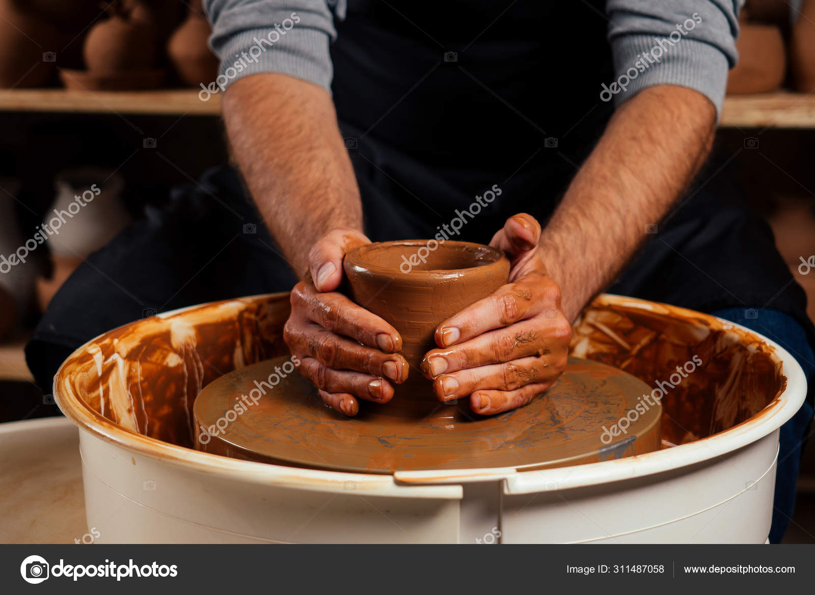 potter professional happy man working with brown clay in workshop . Stock  Photo by yurakrasil