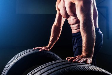 Kaslı fitness adamı, antika heykel mükemmel kaslar, altı paket karın kası ve stüdyo arka planında lastik çeviren çıplak vücut geliştirici. Fonksiyonel antrenman spor salonunu kabul et
