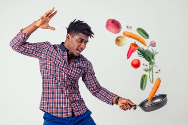 Afro-amerikan şef mutfağı elinde sihirli yemek salatası, havuç, sarımsak, soğan, biber, patates, salatalık, beyaz arka plan stüdyosu.