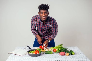 Afro-amerikan şef mutfağı elinde sihirli yemek salatası, havuç, sarımsak, soğan, biber, patates, salatalık, beyaz arka plan stüdyosu.