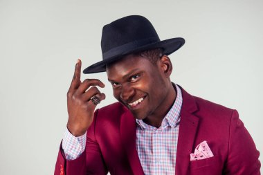 Retro tarzı iyi giyimli Afro-Amerikan iş adamı modeli kırmızı takım elbiseli ve siyah şapkalı beyaz arka planda stüdyo.