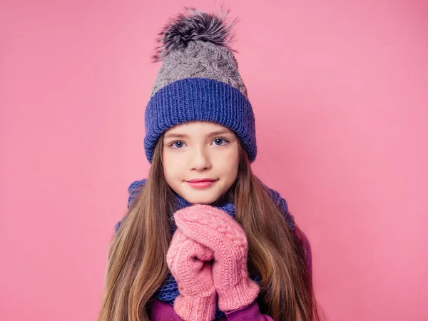 Retrato bonito menina em quente tricotado colorido cinza azul chapéu, cachecol e luvas enviando soprando um beijo de ar no fundo rosa no studio.Children inverno outono roupas — Fotografia de Stock