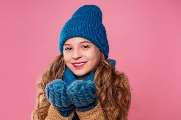 Retrato bonito menina em quente tricotado colorido chapéu verde, cachecol e mitenes enviando soprando um beijo de ar no fundo rosa no studio.Children inverno outono roupas — Fotografia de Stock