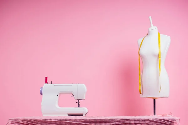 Шитье шаблон, швейная машина и маникен в студии розовый фон. Портной создает коллекцию нарядов, шьет одежду в мастерской. молодая женщина дизайнер одежды отмечает идеи — стоковое фото