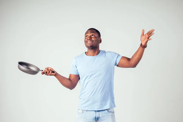Africký americký kuchař kuchyňský kout drží pánev kouzelník vaření magie létání jídlo salát, mrkev, česnek, cibule, pepř, brambory, okurka izolovat bílé pozadí studio.magic chuti fantazie — Stock fotografie