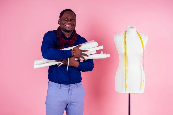 African American man tailor seamstress workshop stylish male model clothes designer posing next to the mannequin on pink background in the studio hands point to design space copyspace