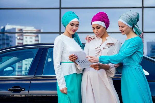 Группа из трех успешных бизнес-транснациональных мусульманских женщин в стильном хиджабе с завуалированной головной платок связан на голове общаться и говорить о работе офиса в уличном небоскребе зрения — стоковое фото