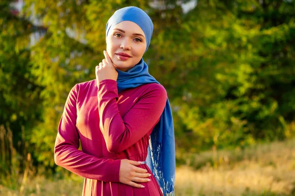 Islamische schöne Frau in einem muslimischen jungfräulichen Kleid steht auf einem Sommer Park Straße Hintergrund Wald Herbst Bäume — Stockfoto