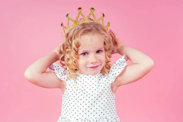 Little girl beauty queen blue eyes, curls blonde hairstyle with a tiara crown on her head in a cute white dress in peas posing in the studio on a pink background.birthday celebration,Beauty contest — Stock Photo, Image