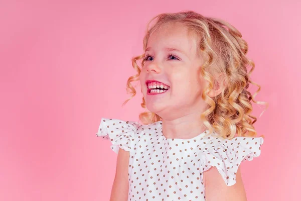 Little girl beauty queen blue eyes, curls blonde hairstyle with a tiara crown on her head in a cute white dress in peas posing in the studio on a pink background.birthday celebration,Beauty contest — Stock Photo, Image