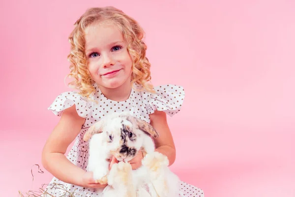 Little blonde girl with a bunny rabbit easter in studio pink background.beautiful female kid celebrating Easter Holiday with pets,child painted eggs.dream and birthday present.Alice in Wonderland — Stock Photo, Image