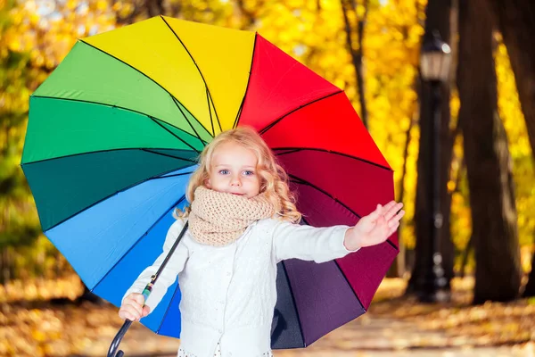 Glücklich lustig schöne Blondine mit blauen Augen Kind mit Regenbogen bunten Regenschirm im Herbst Park. Mädchen spielen in der Natur im Freien. Familienspaziergang im Septemberwald gelbe Bäume Blätter — Stockfoto