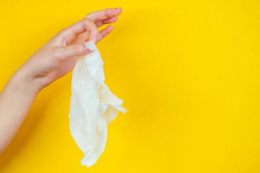El, sarı arka planda kirli kullanılmış bir peçeteyi tutuyor.