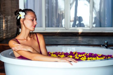 Plumeria saçlı, kırmızı sütyenli, tropik çiçekli, organik cilt bakımlı, lüks kaplıca oteli olan bir kadın.