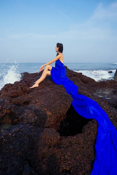 Мода красива жіноча модель позує на пляжі з камінням в довгій сукні метелика хамелеона водоспад спідниці плюм-поїзд.чуттєві парфуми з красивою і молодою брюнеткою жінкою хвилястий тропічний пісок — стокове фото