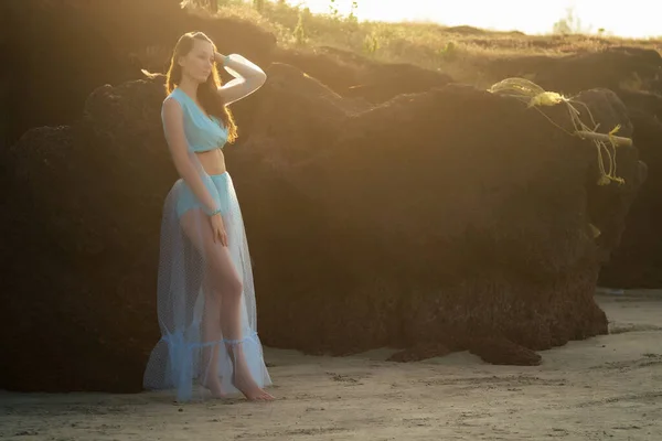Красива молода жінка в стильній синій довгій сукні, насолоджуючись день на пляжі — стокове фото