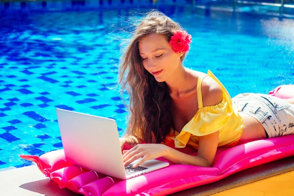 remote work dream job.young woman sitting on inflatable pink mattress in the swimming pool having sunbath and working on laptop.girl eating exotic fruits tropical mango, pineapple and dragon fruit