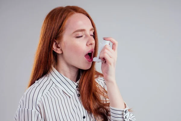 Pelirroja empresaria turista estudiante en una camisa a rayas con asma usando el inhalador de asma por ser saludable estudio de fondo blanco — Foto de Stock