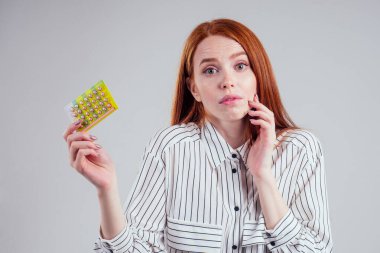 picture of young redhead businesswoman in striped shirt with one pack of pills white background studio clipart