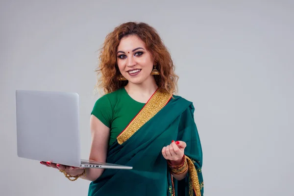 remote working concept dream job.beautiful and young indian businesswoman green stylish sari working with a laptop while sitting in a summer studio white