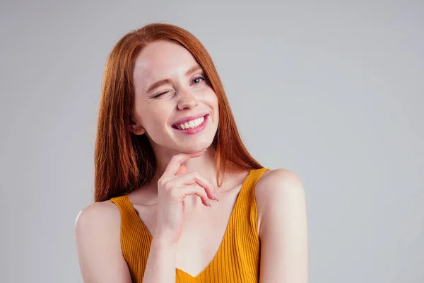 Счастливые красивые рыжие волосы белая женщина с идеальной кожей и очаровательной белоснежной улыбкой в желтой рубашке, глядя подмигивая на камеру белый студийный фон . — стоковое фото
