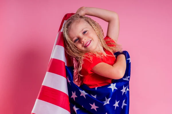 Blue eyes blonde charming female kid celebration independence holding a paper torch and diy crown and american flag on a pink background in the studio.English language learning concept and freedom — Stock Photo, Image