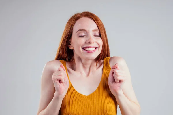 Счастливая веселая рыжая молодая женщина с идеальной кожей в желтой рубашке, смотрящая в камеру с радостным и очаровательным белоснежным фоном студии улыбки . — стоковое фото